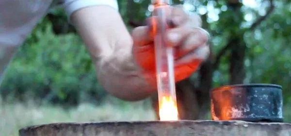 Laboratory experiment with hand holding a test tube above an open flame.