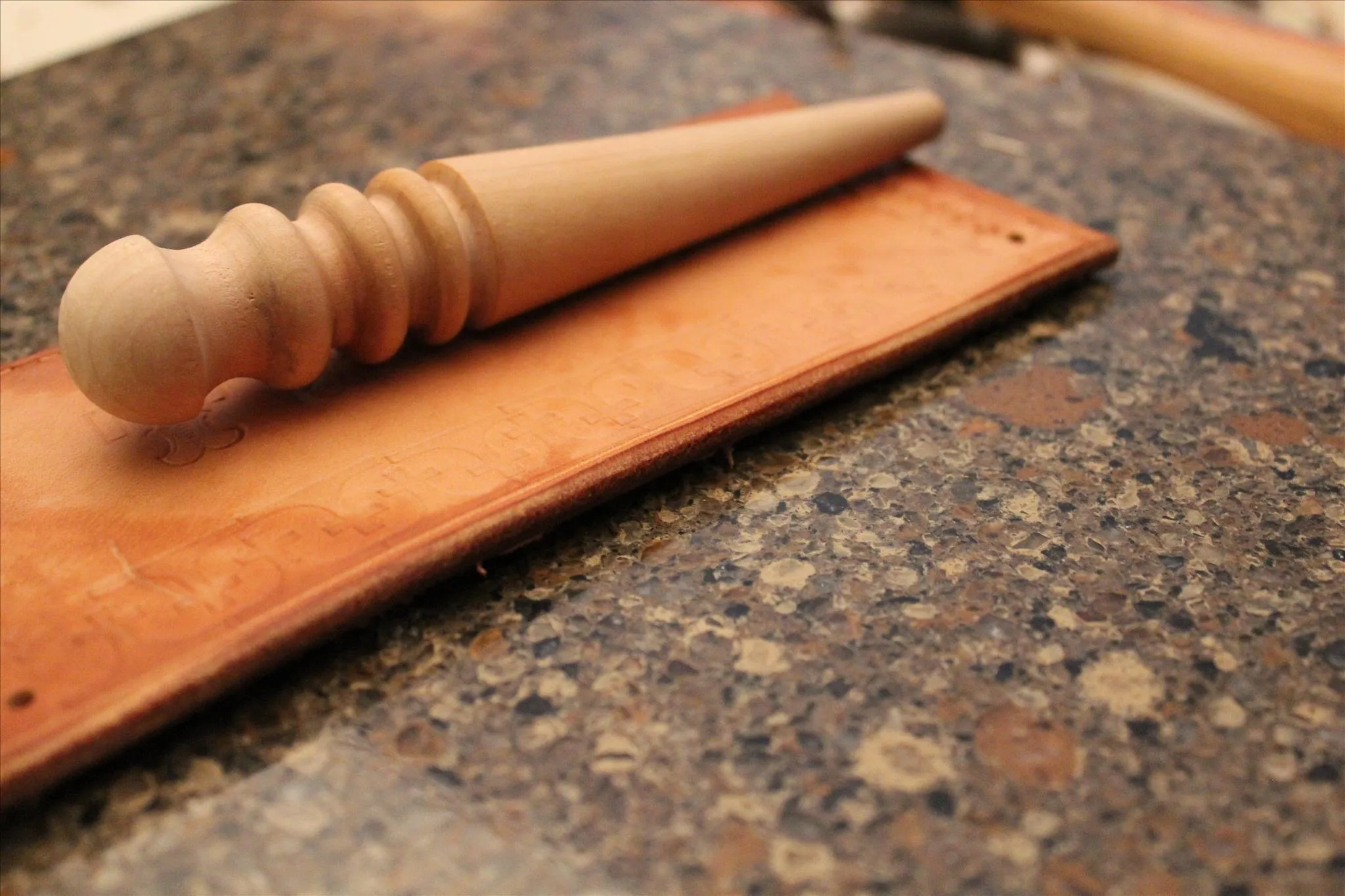 Wooden tool on leather work surface.