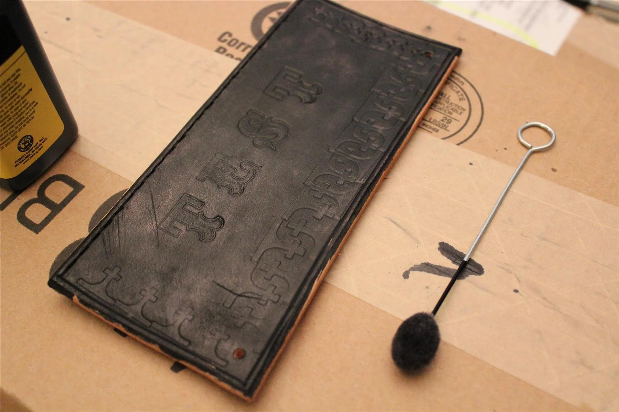 Antique leather-bound notebook with a metal stylus on a surface.