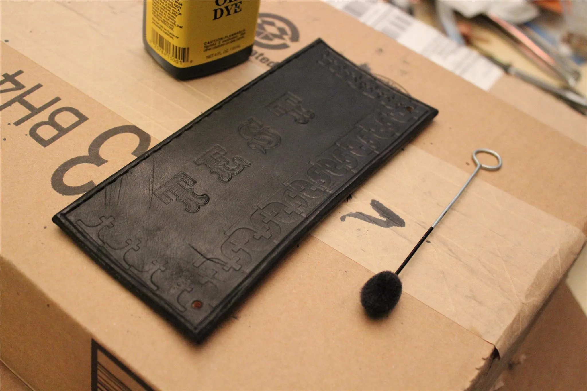 Black rubber stamp on a cardboard surface with an ink bottle and a brush.