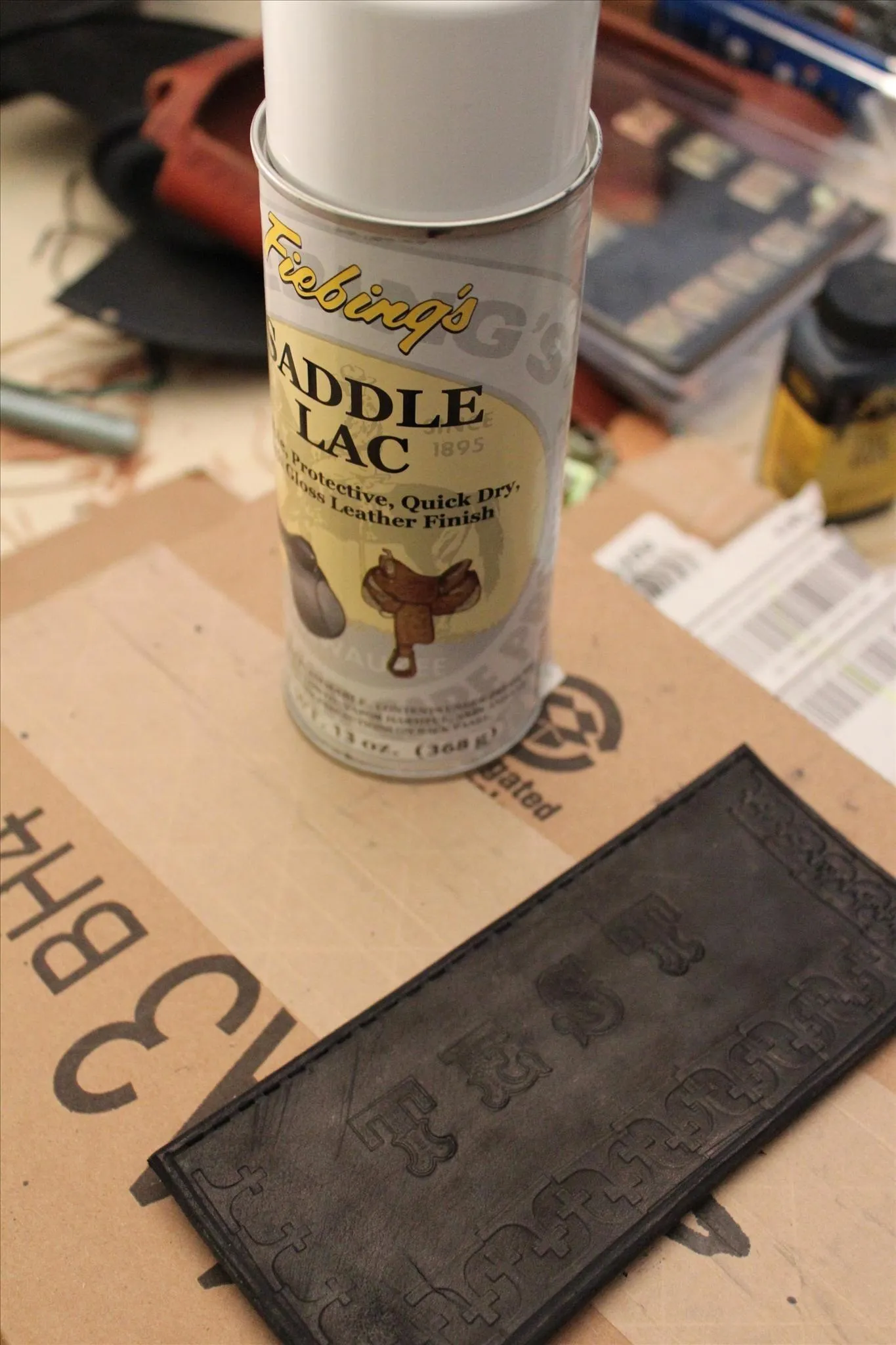 Can of saddle lac spray paint next to a black-painted object on a work surface.