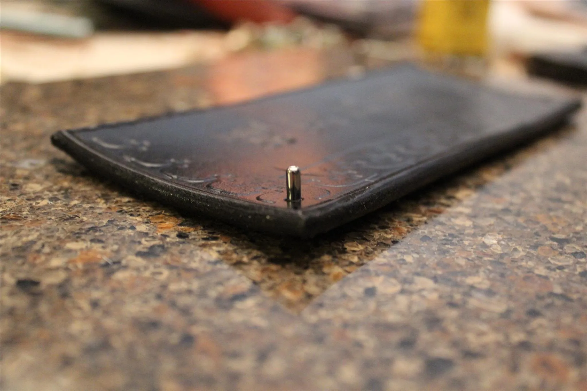 Leather wallet with a small metal emblem on a textured surface.