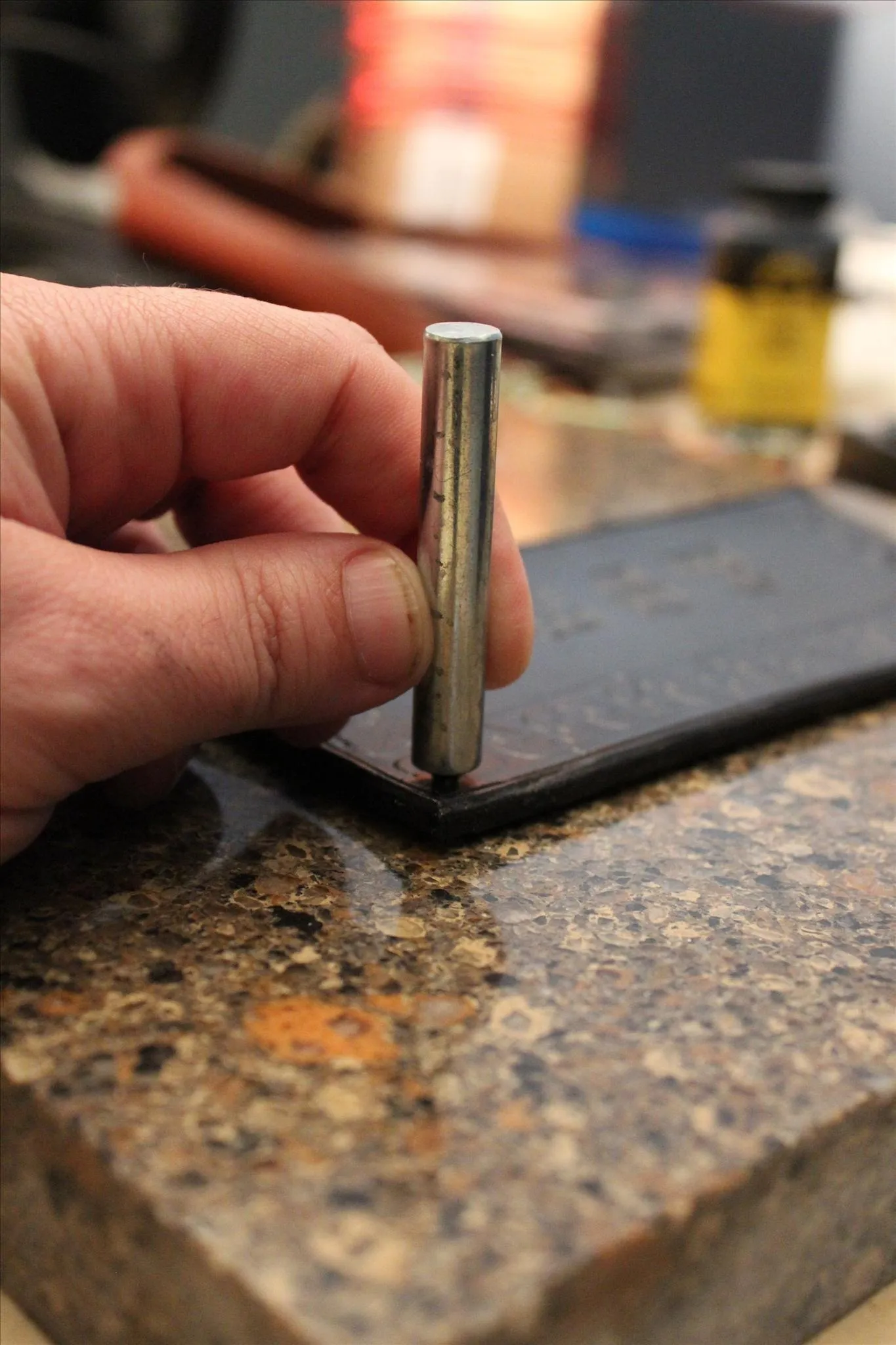 Metal stamp being pressed onto leather.