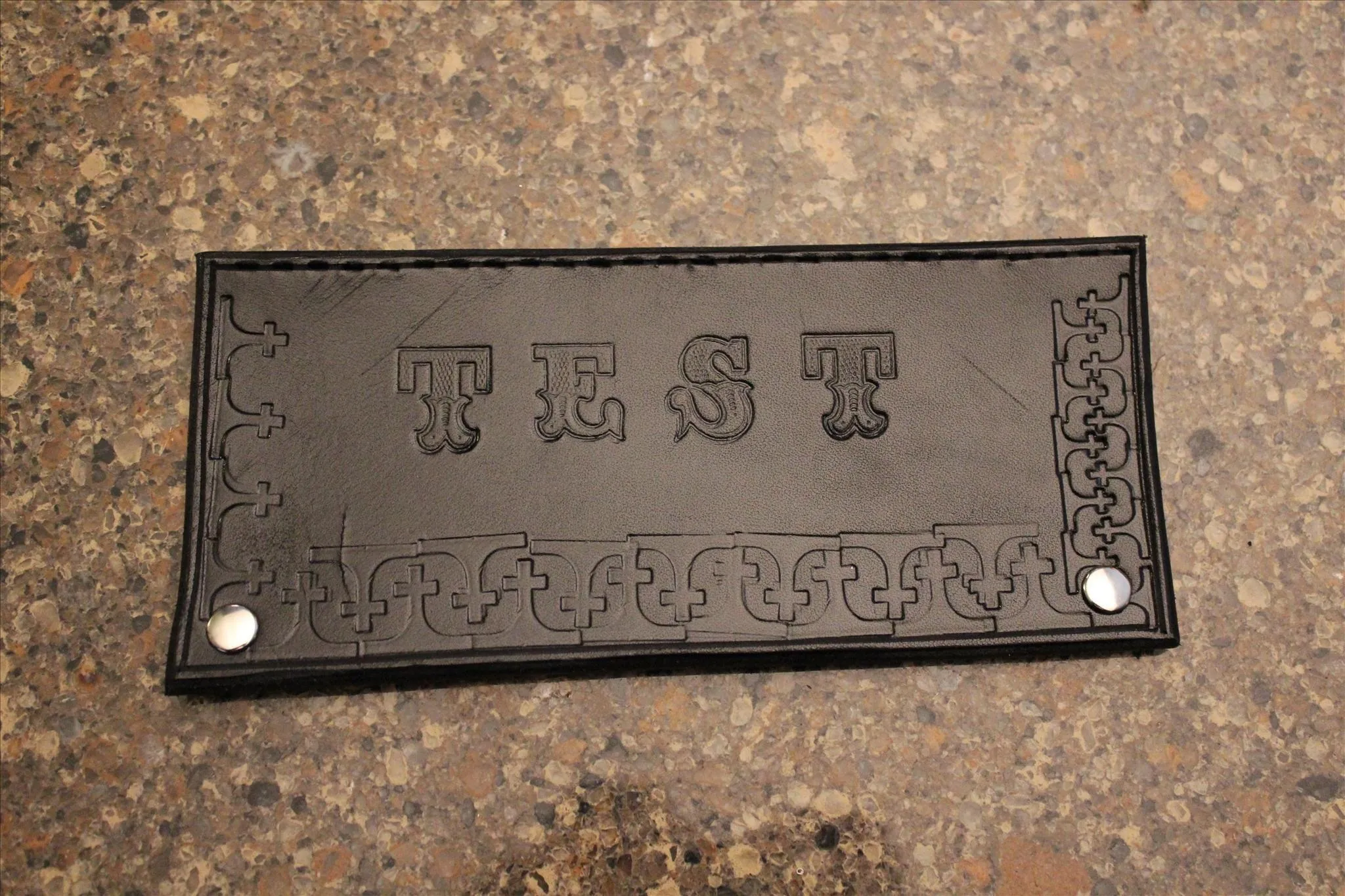 Leather block with embossed letters spelling "TEST."