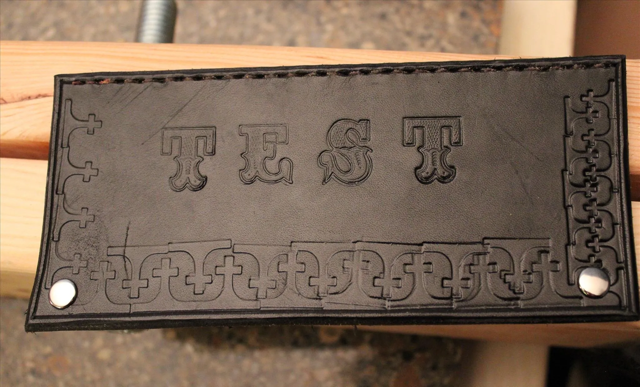 Embossed leather piece with the word "TEST" and decorative border.