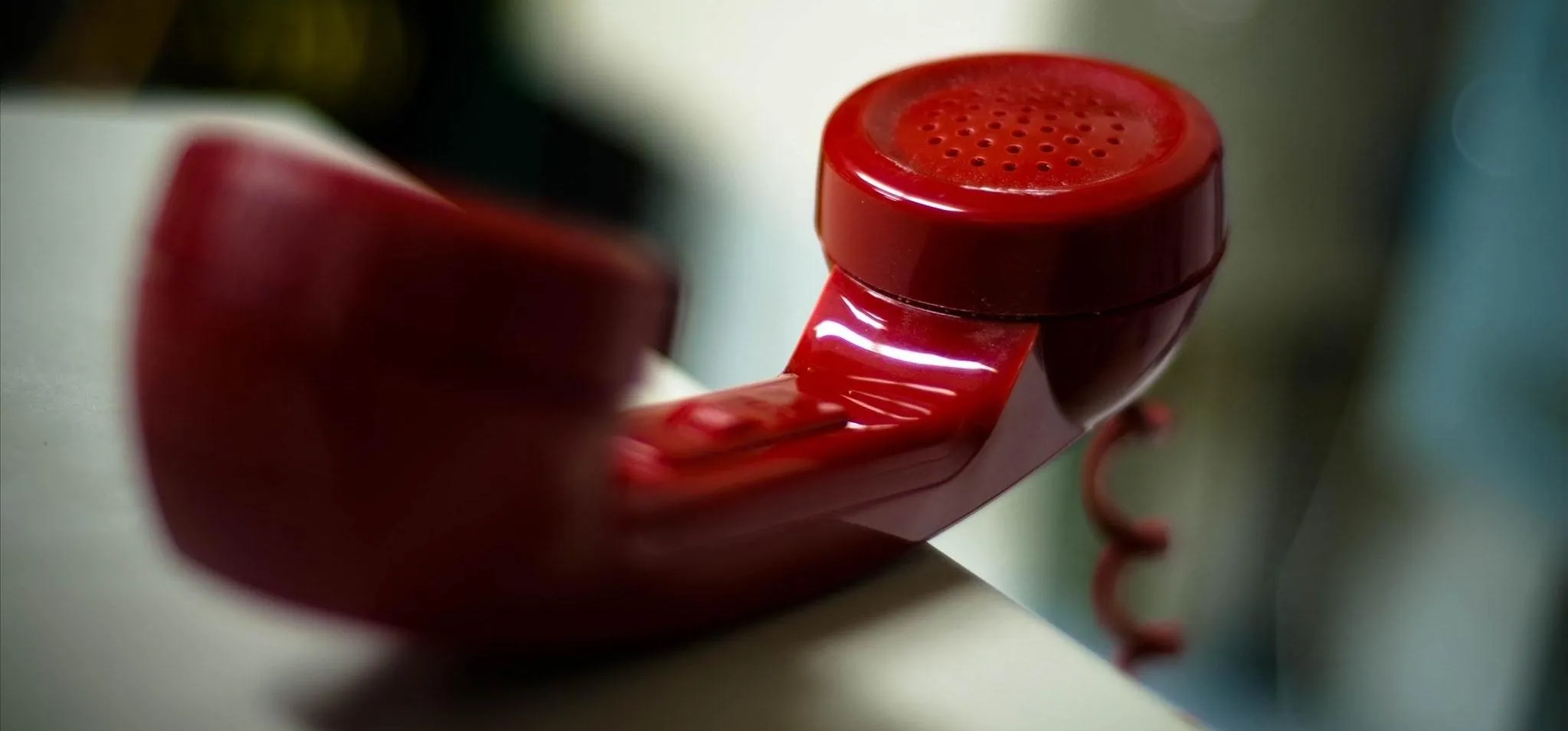 Red vintage telephone receiver on a table.