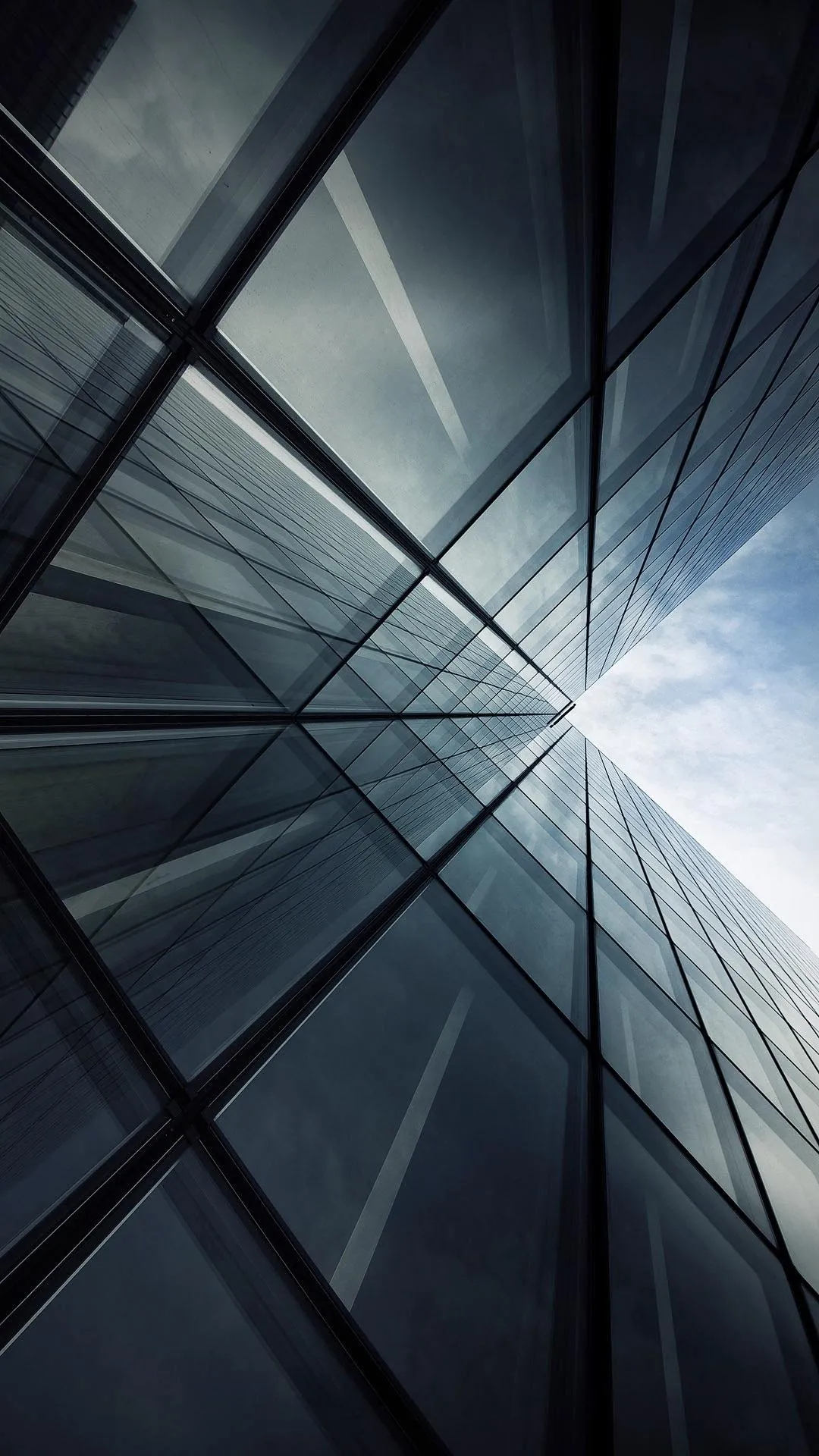 Modern architectural glass facade with angular reflections.