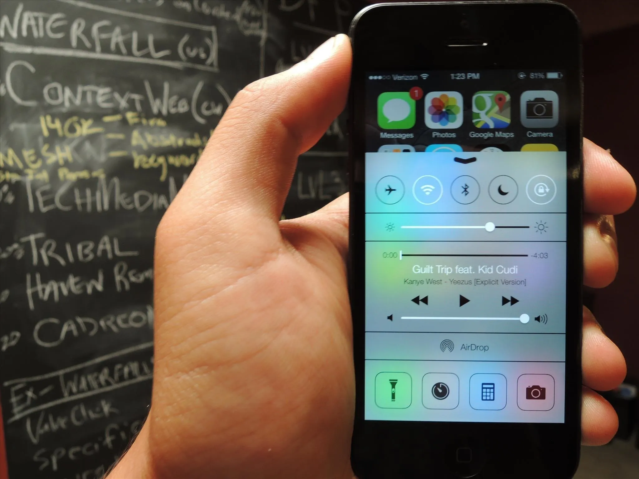 A hand holding a smartphone displaying a control center interface.