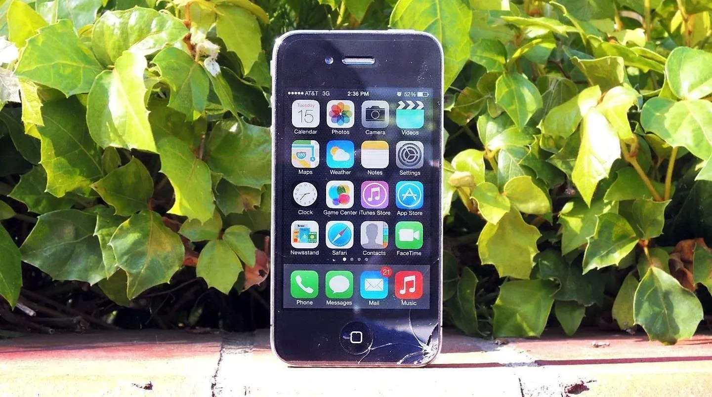 iPhone with apps displayed against a background of green foliage.