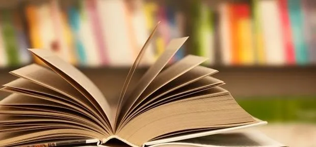 Open book with blurred bookshelves in the background.