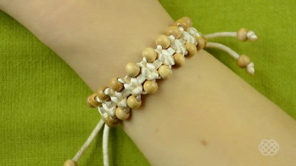 Beaded bracelet on a wrist against a green background.