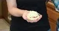 Hands preparing a meal, adding ingredients to a dish.