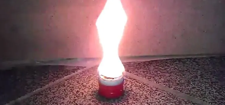 Flame emerging from a candle holder on a textured surface.