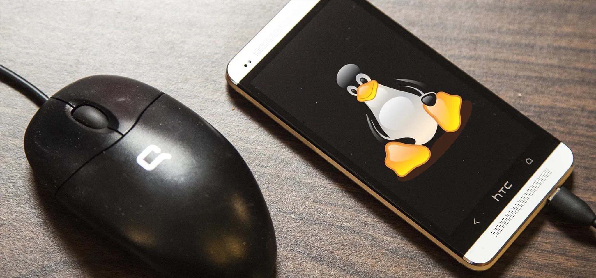 A smartphone displaying the Linux Tux mascot beside a computer mouse.