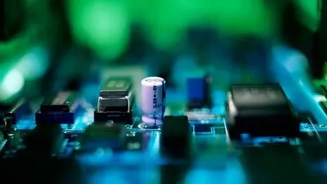 Close-up of electronic circuit components with a green illuminated background.