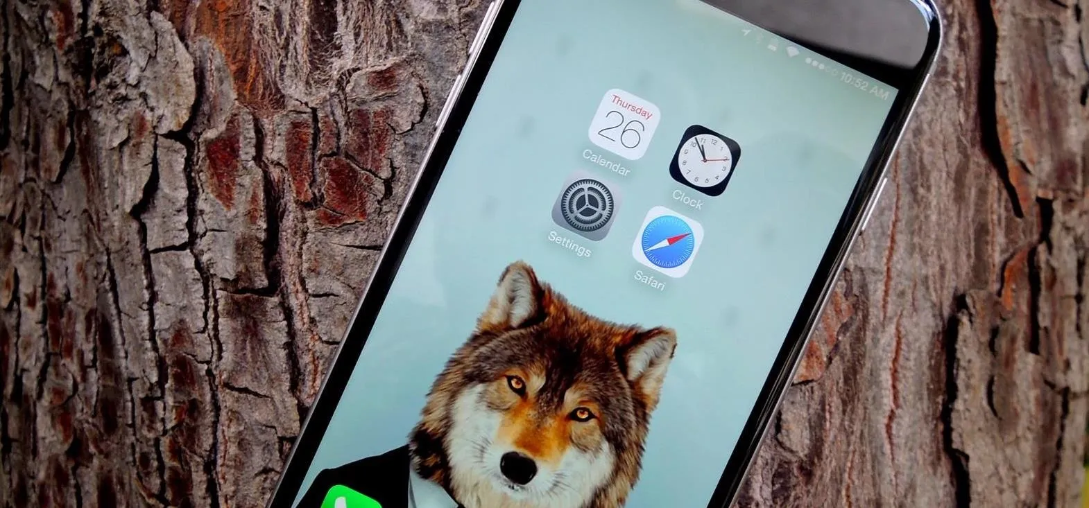 Phone displaying a wolf image as wallpaper against a wooden background.