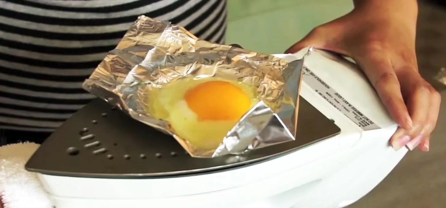 Cooking an egg using an iron and aluminum foil.