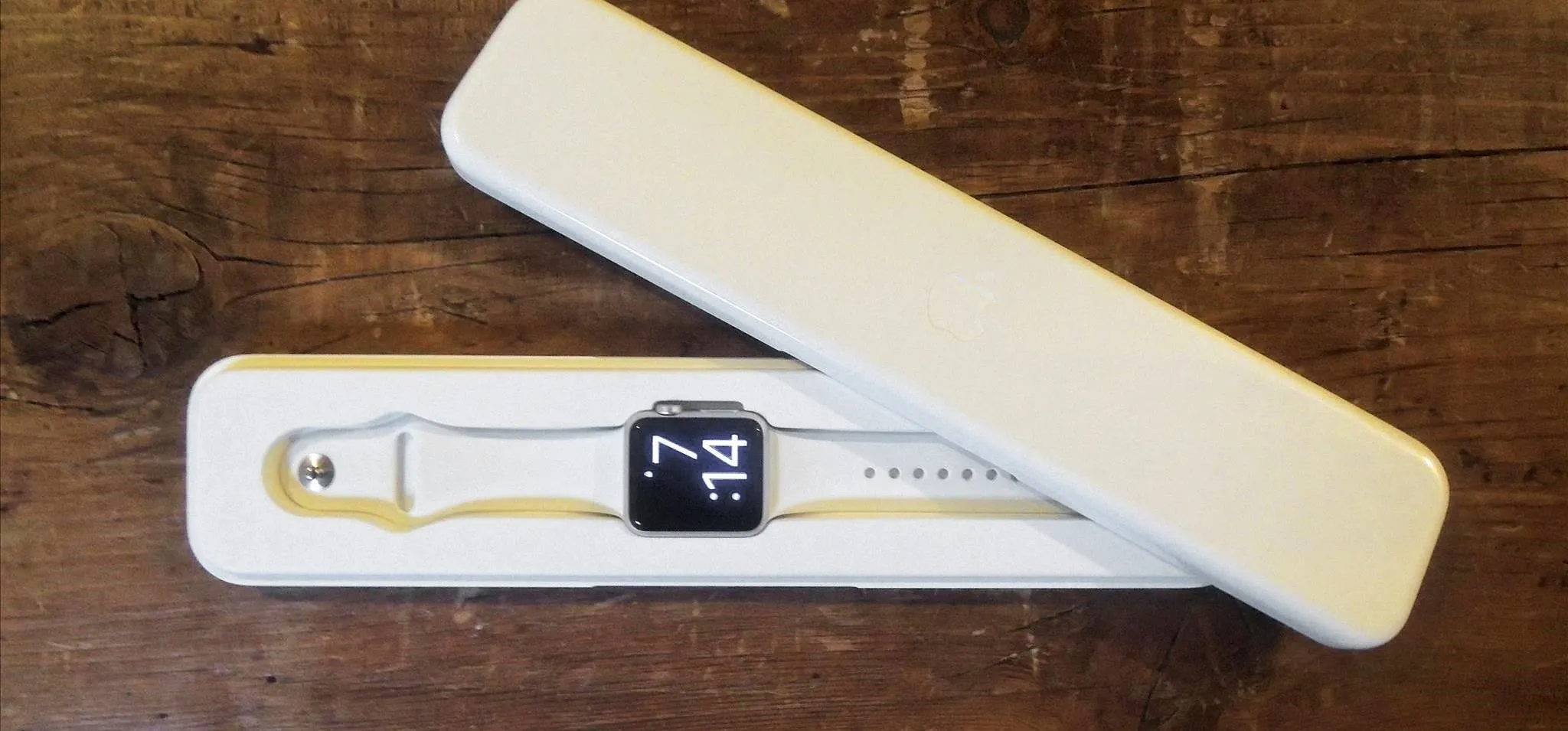 Smartwatch in a sleek white box on a wooden surface.