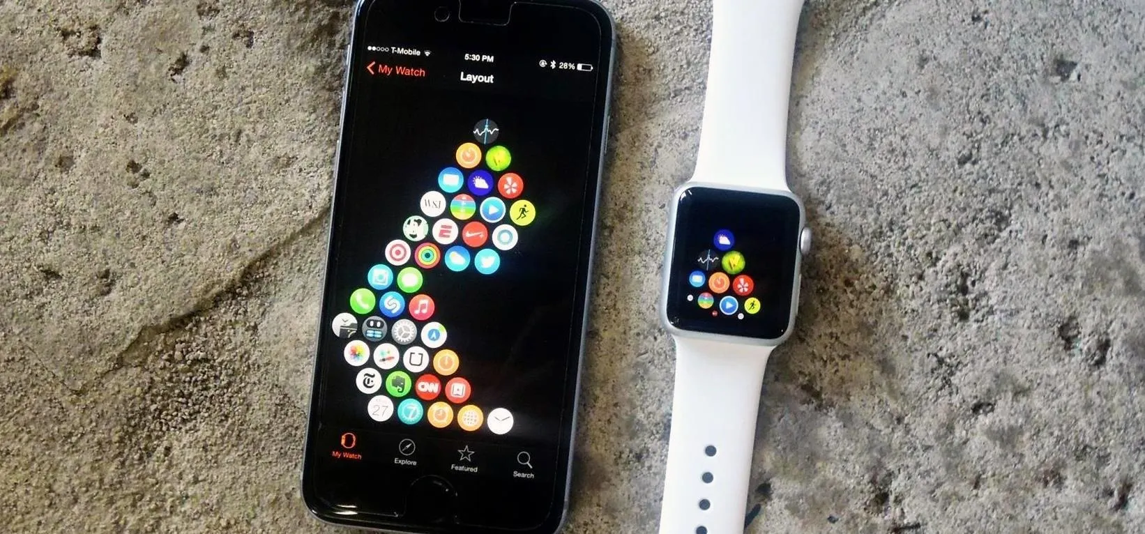 Smartphone and smartwatch displaying colorful app icons on a textured surface.