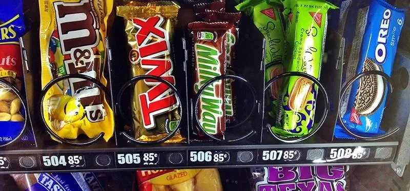 Vending machine displaying a variety of snack options including candy bars and chips.