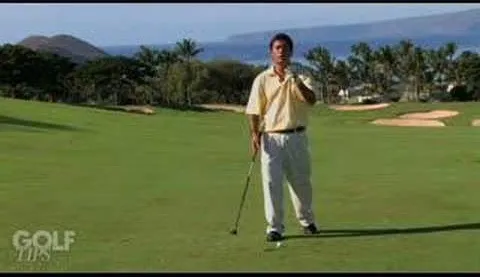 Man standing on a golf course holding a golf club.