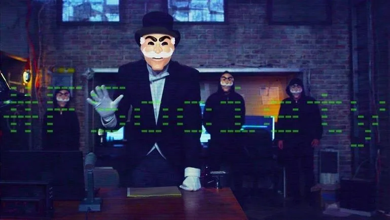 Masked figure in a suit gesturing in a dimly lit room with two shadowy figures in the background.