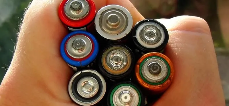 A hand holding various types of batteries.