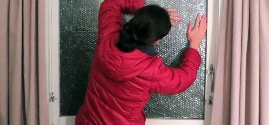 Woman examining a broken glass window.