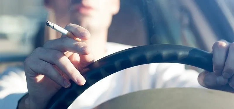 Person driving a car while holding a cigarette.