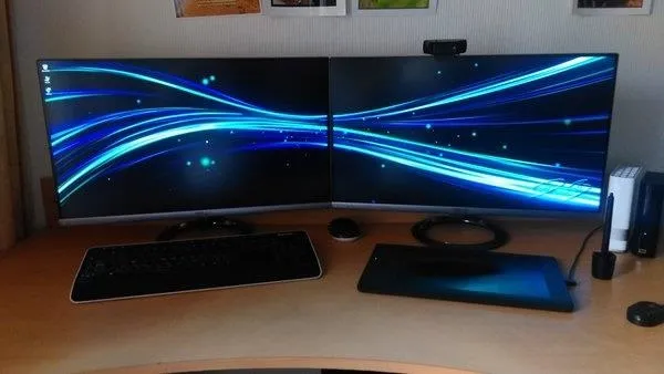 Dual monitor setup with abstract blue light design on screens.