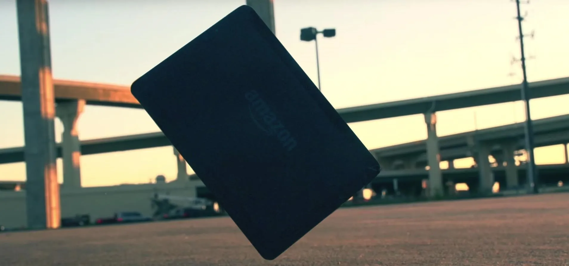 A smartphone floating above a pavement with urban structures in the background.