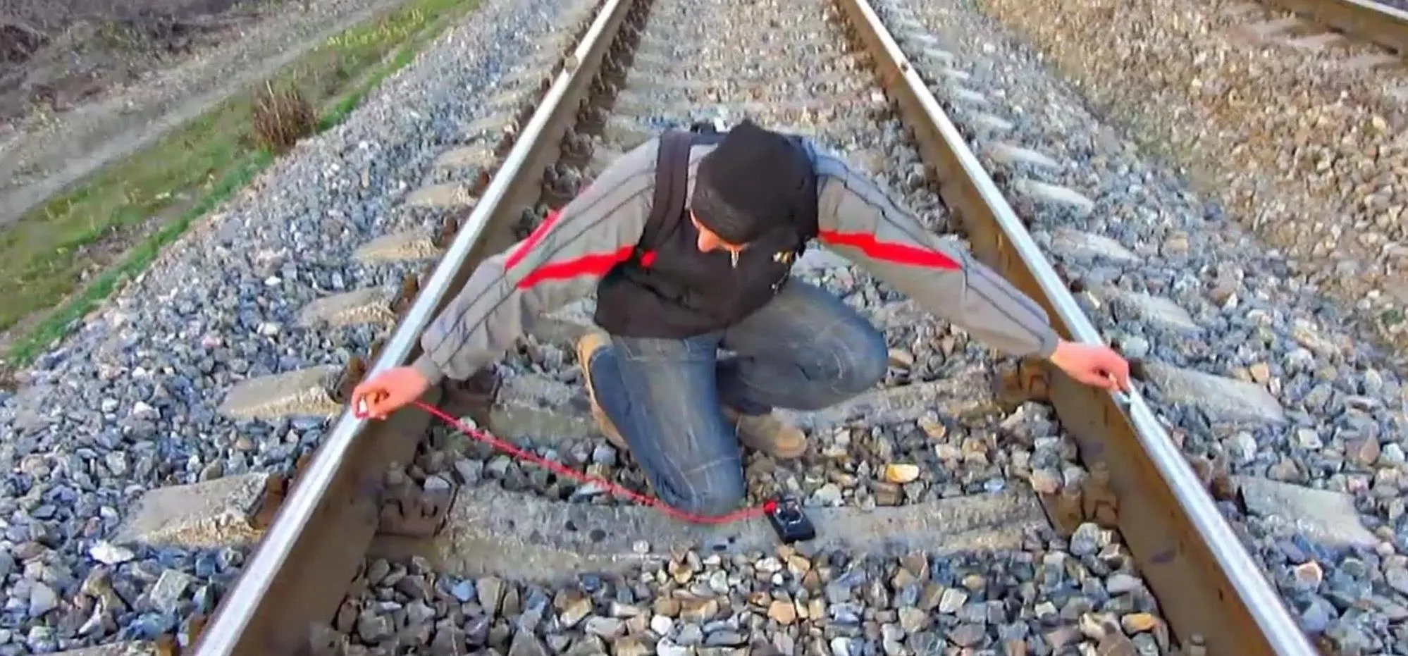 Person measuring distance on railway tracks.