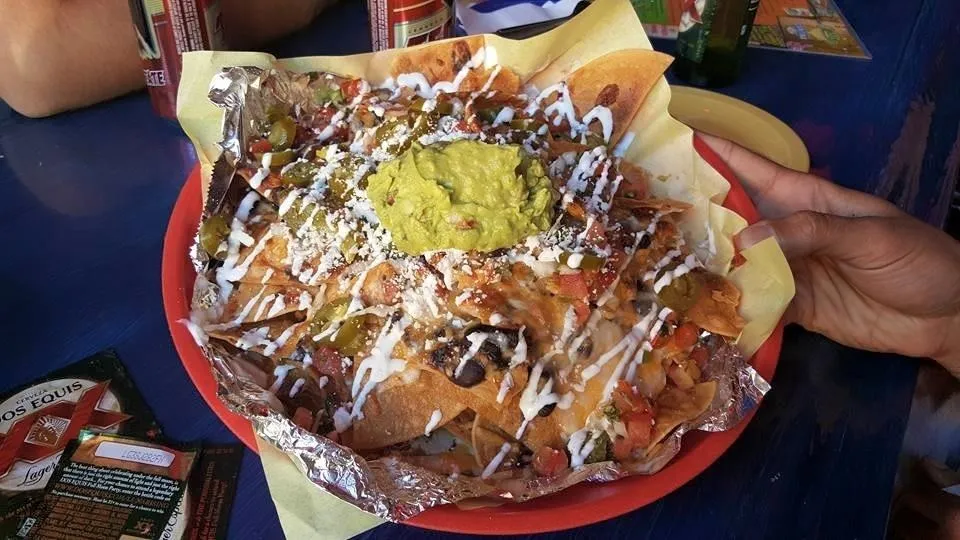 Delicious nachos topped with guacamole, sour cream, and fresh ingredients.