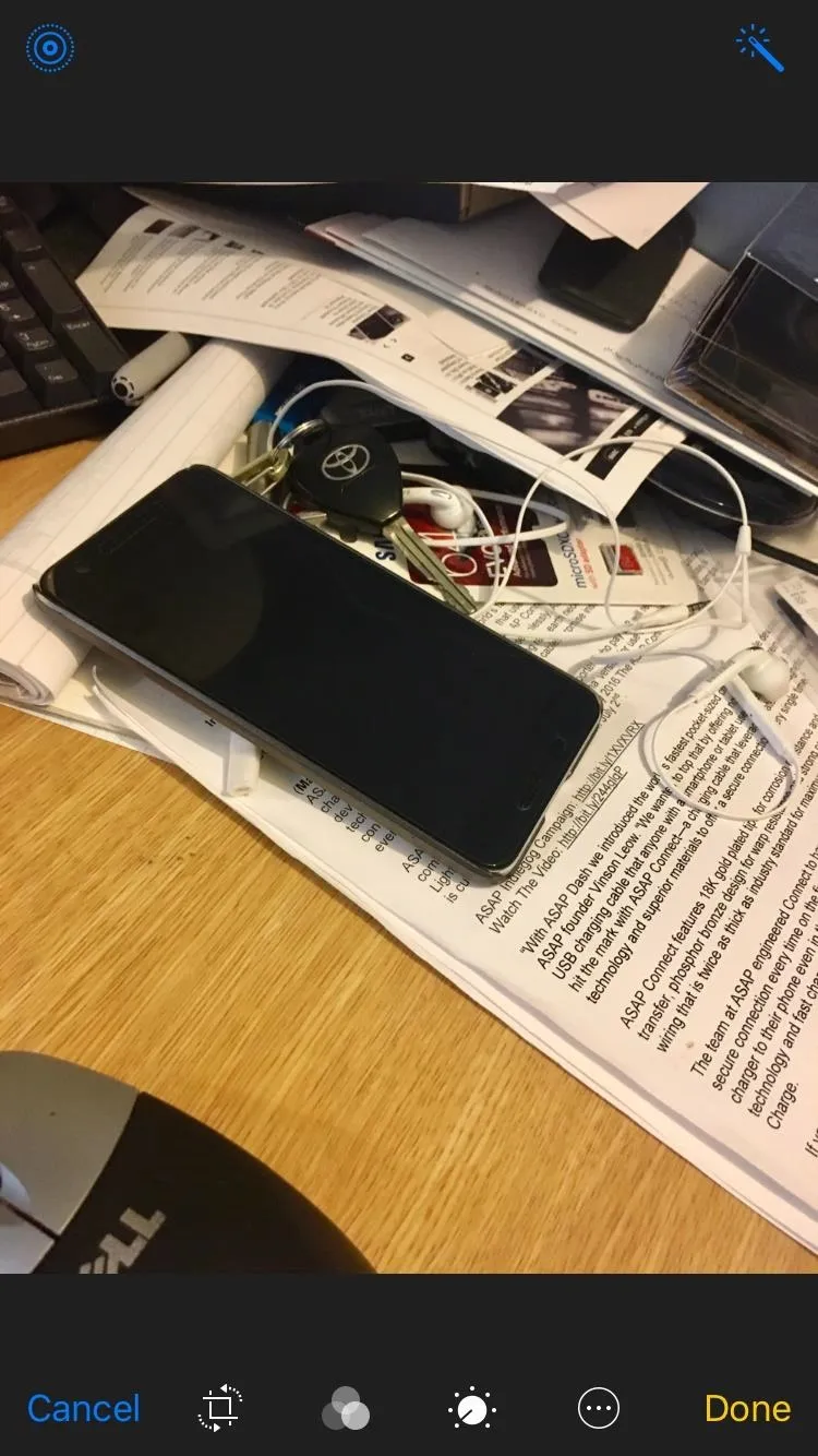 A smartphone lying on a cluttered desk with papers and earphones.