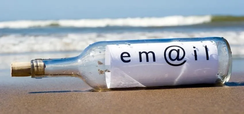 Message in a bottle on a beach with an email address.