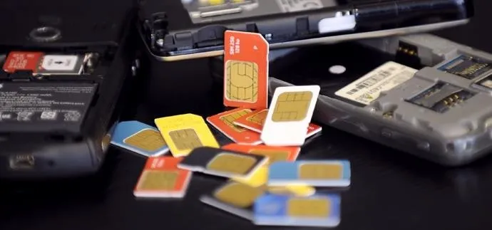 SIM cards and mobile phones on a black surface.
