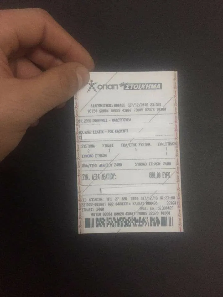 Receipt held in hand against a dark background.