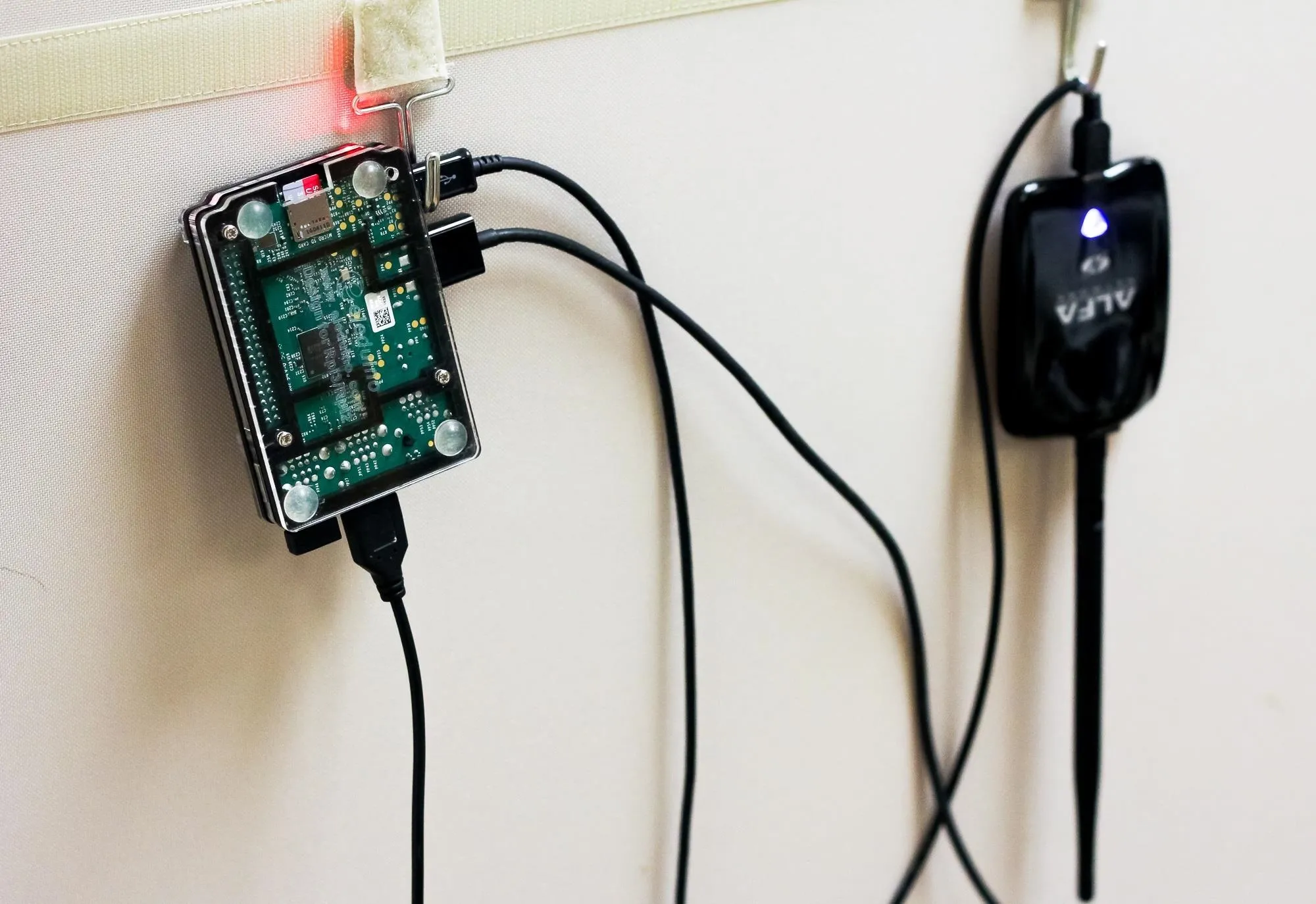 Raspberry Pi connected to a wireless adapter on a wall.