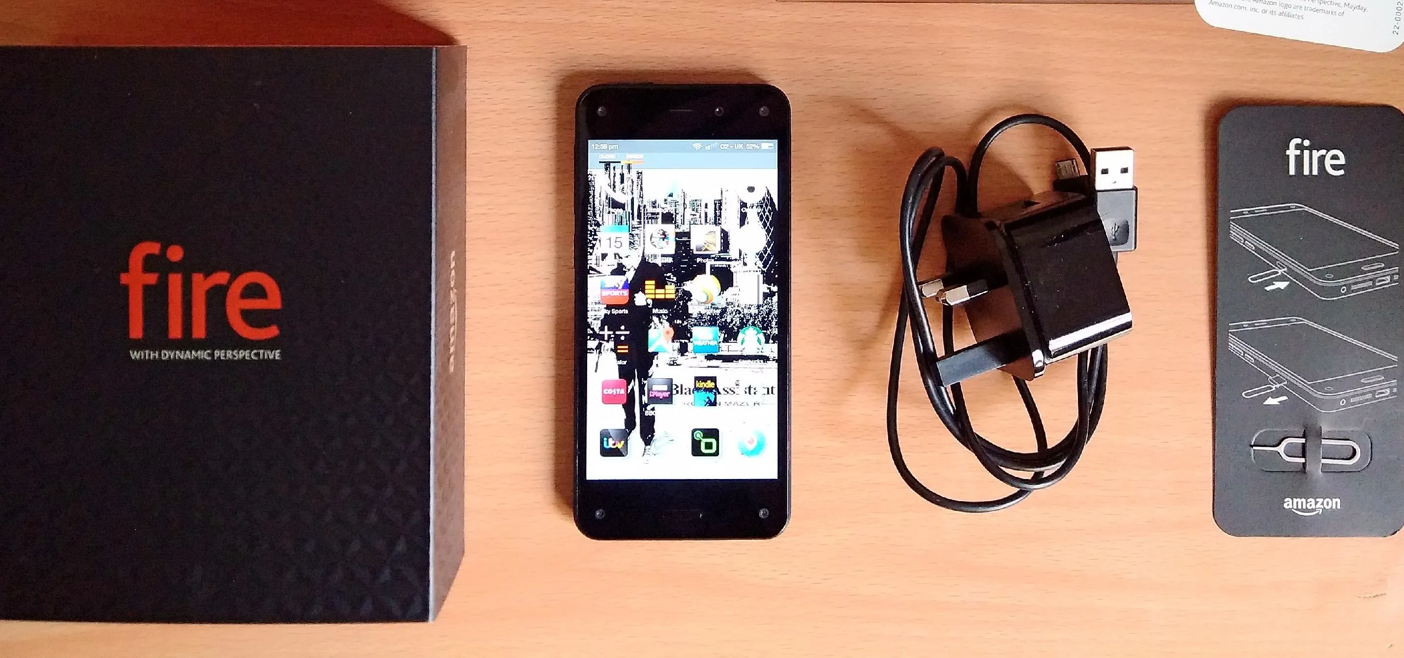 Smartphone with charger and instructional card on a wooden surface.