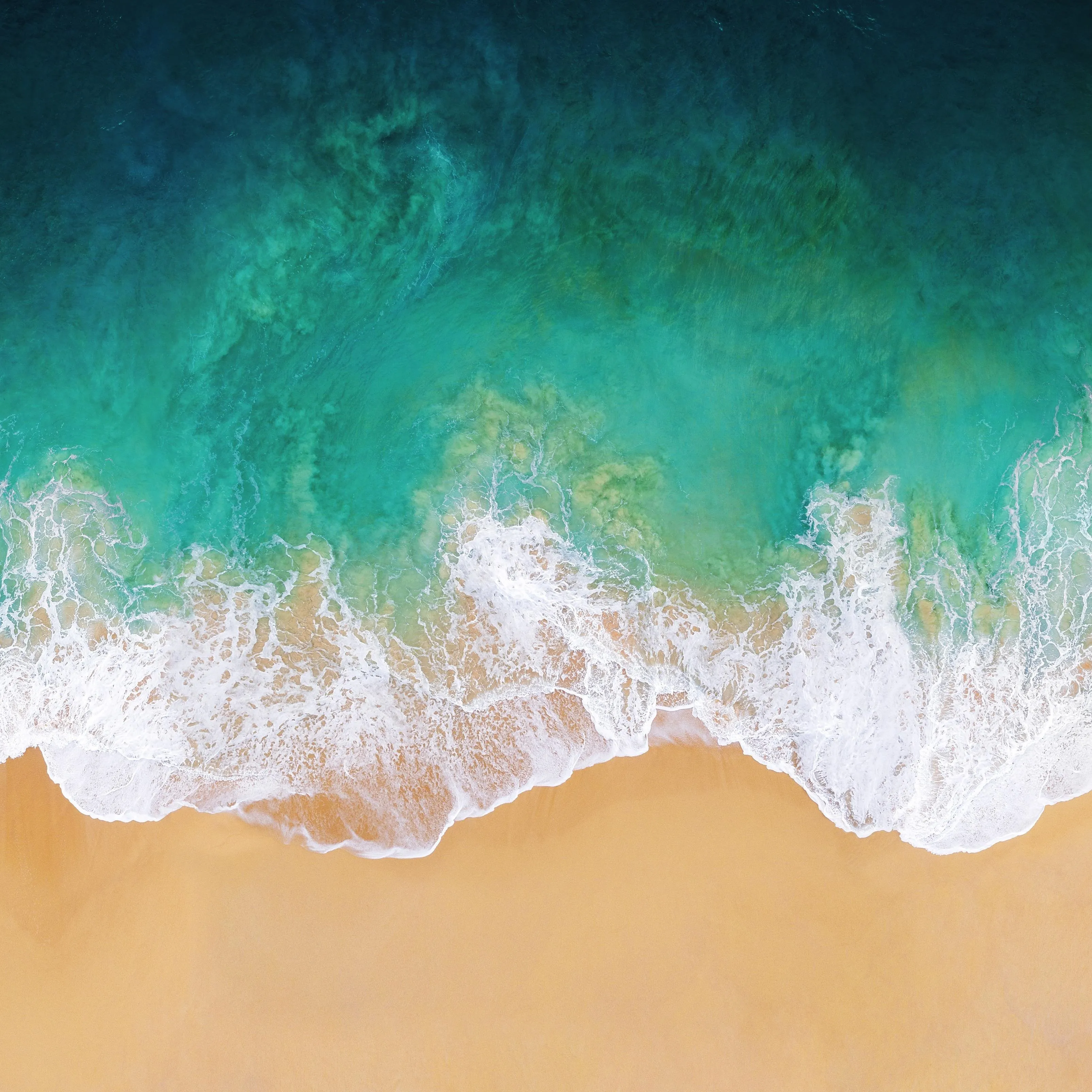 Aerial view of ocean waves crashing onto a sandy beach.