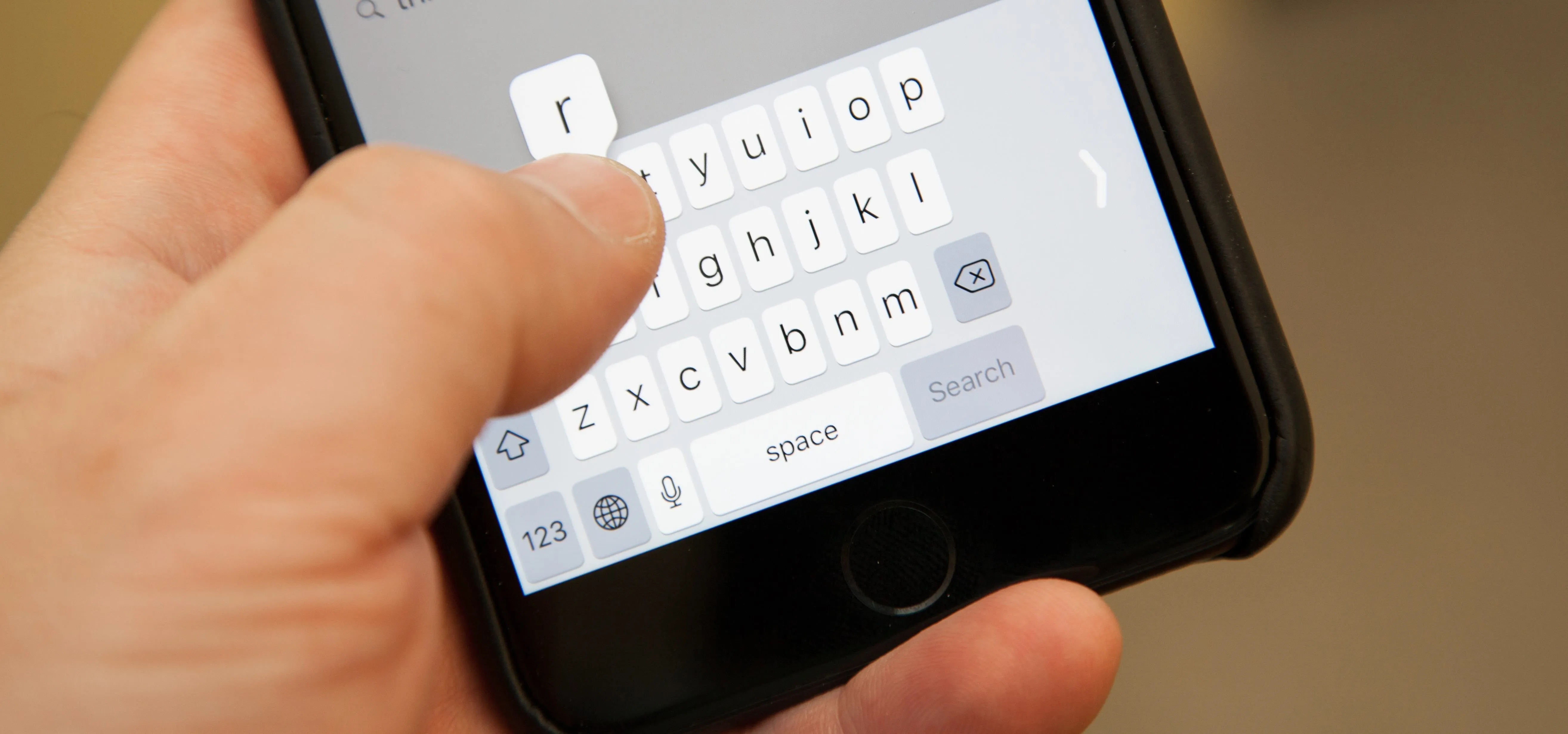 Hand typing on a smartphone keyboard.