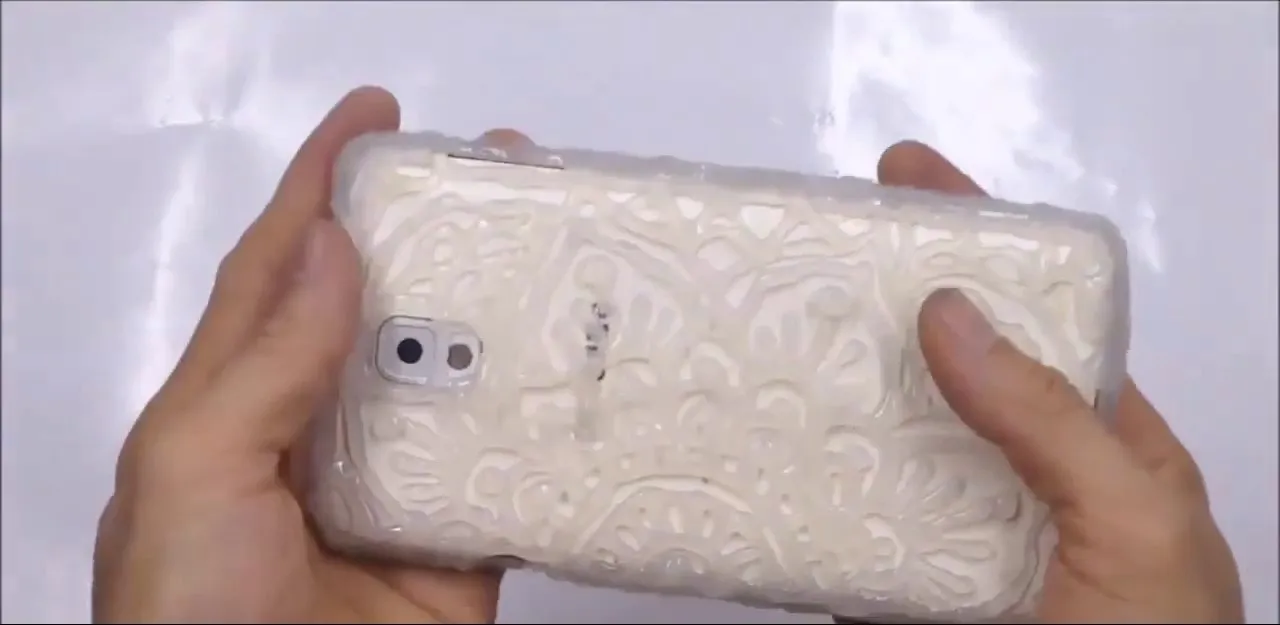 Mobile phone with a textured white case held in hands.