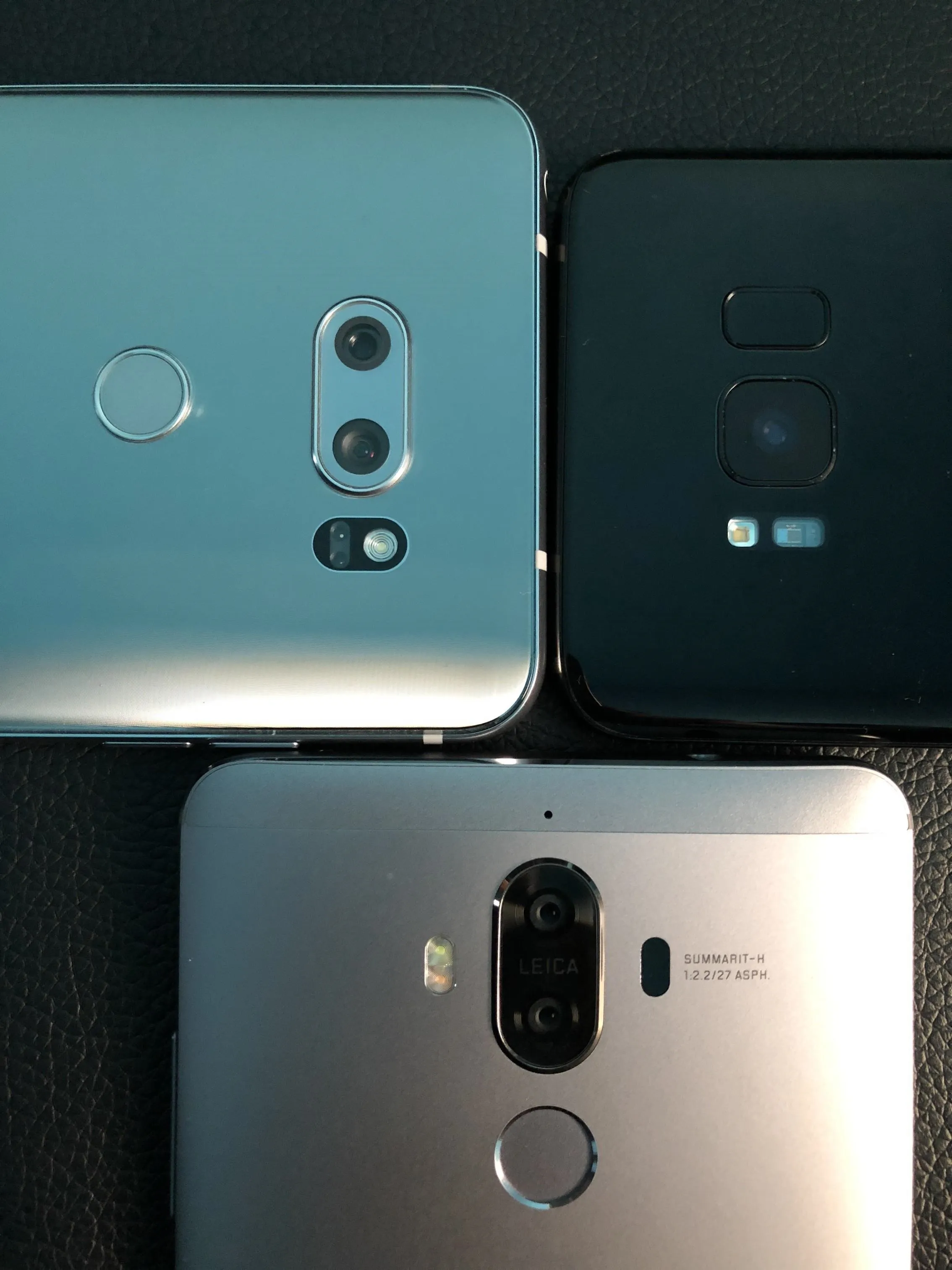 Three smartphones placed close together, showcasing their back designs and camera setups.