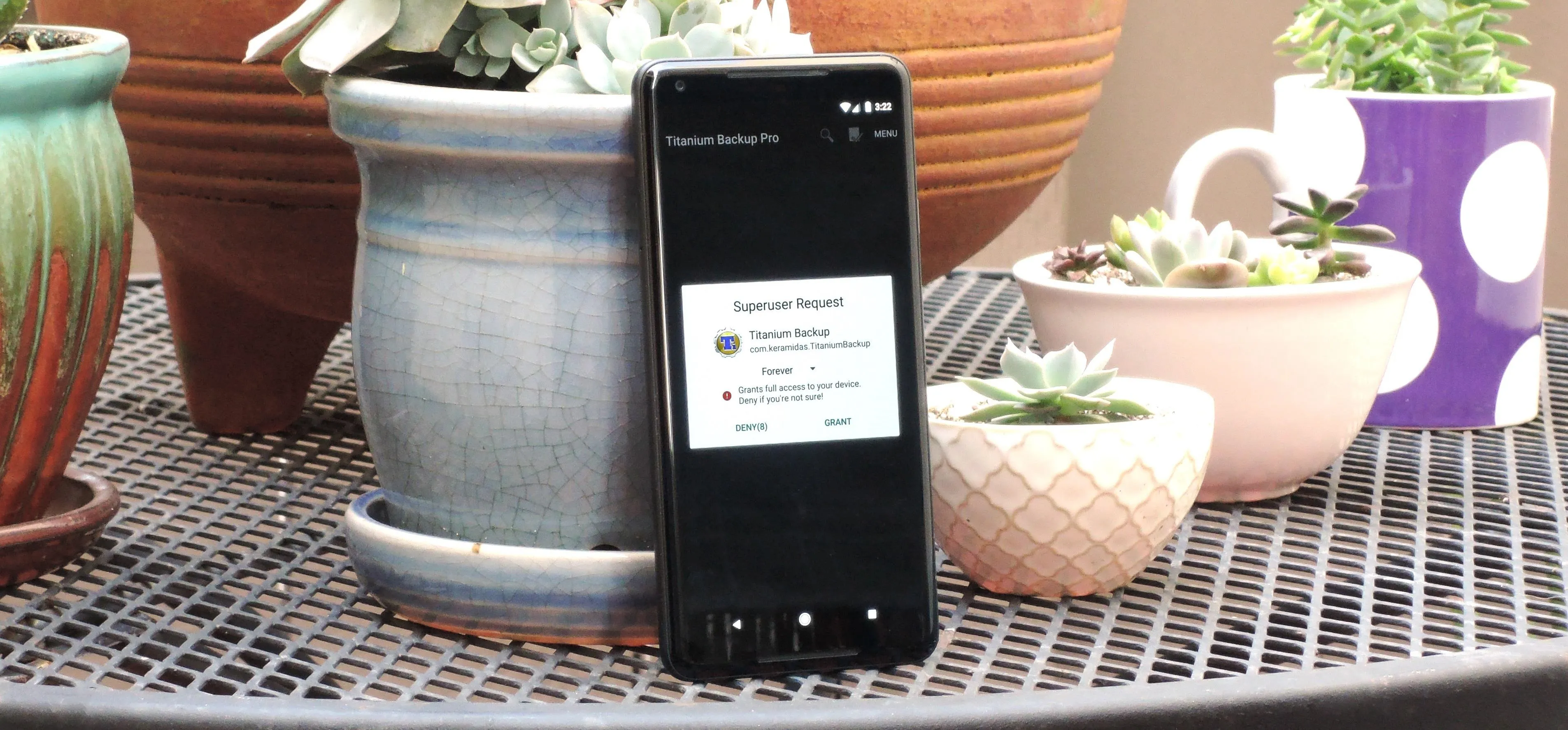 Smartphone next to decorative plant pots on a table.