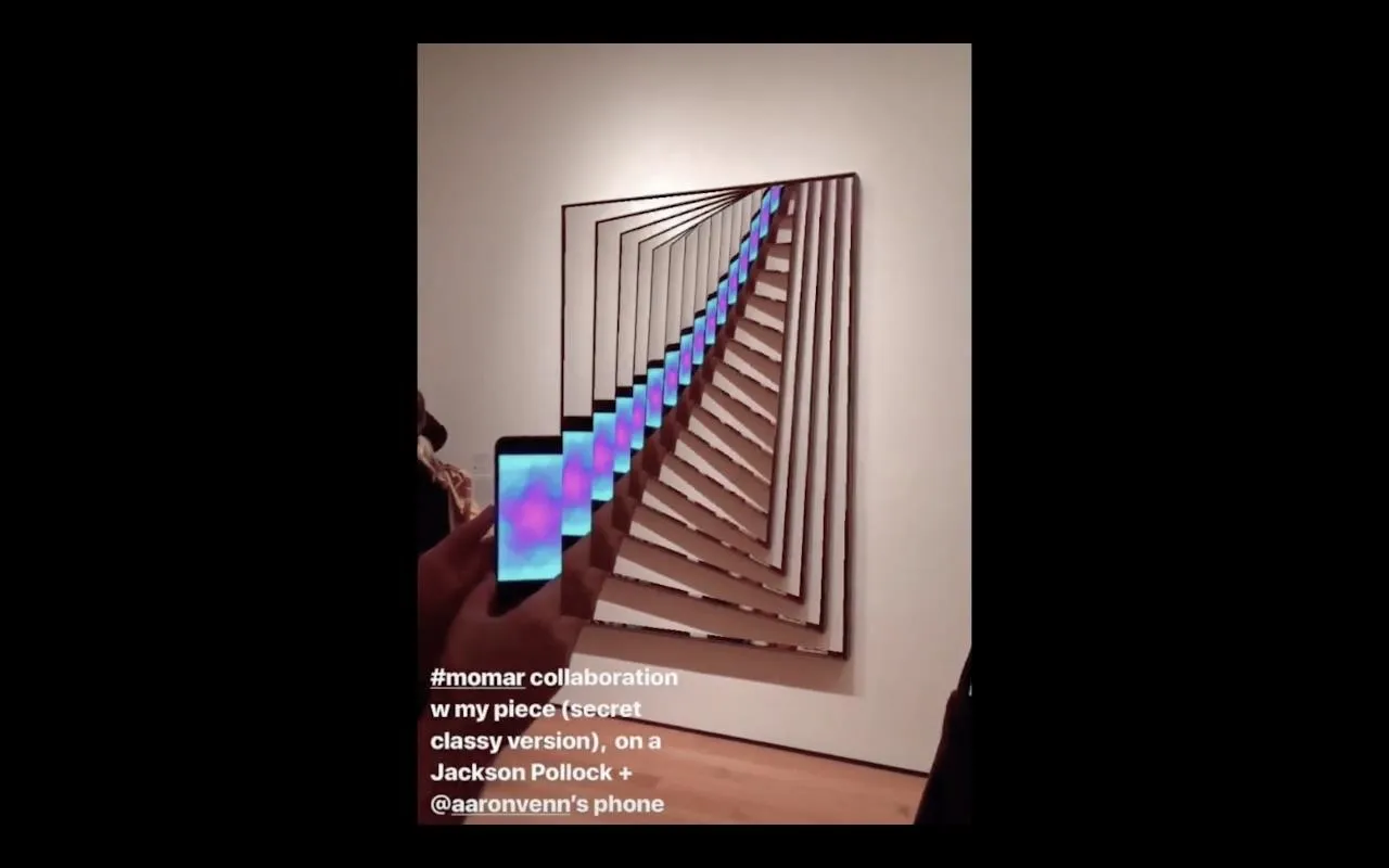 A person holding a smartphone in front of a mirrored artwork creating an infinite tunnel effect.