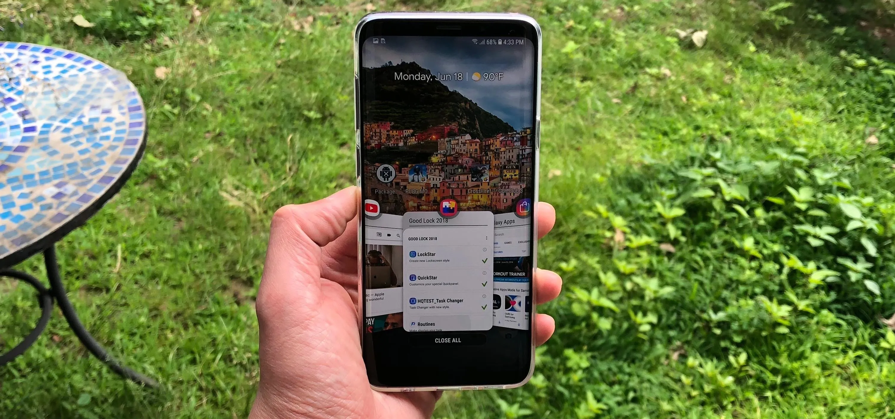 A person holding a smartphone displaying a scenic image outdoors.