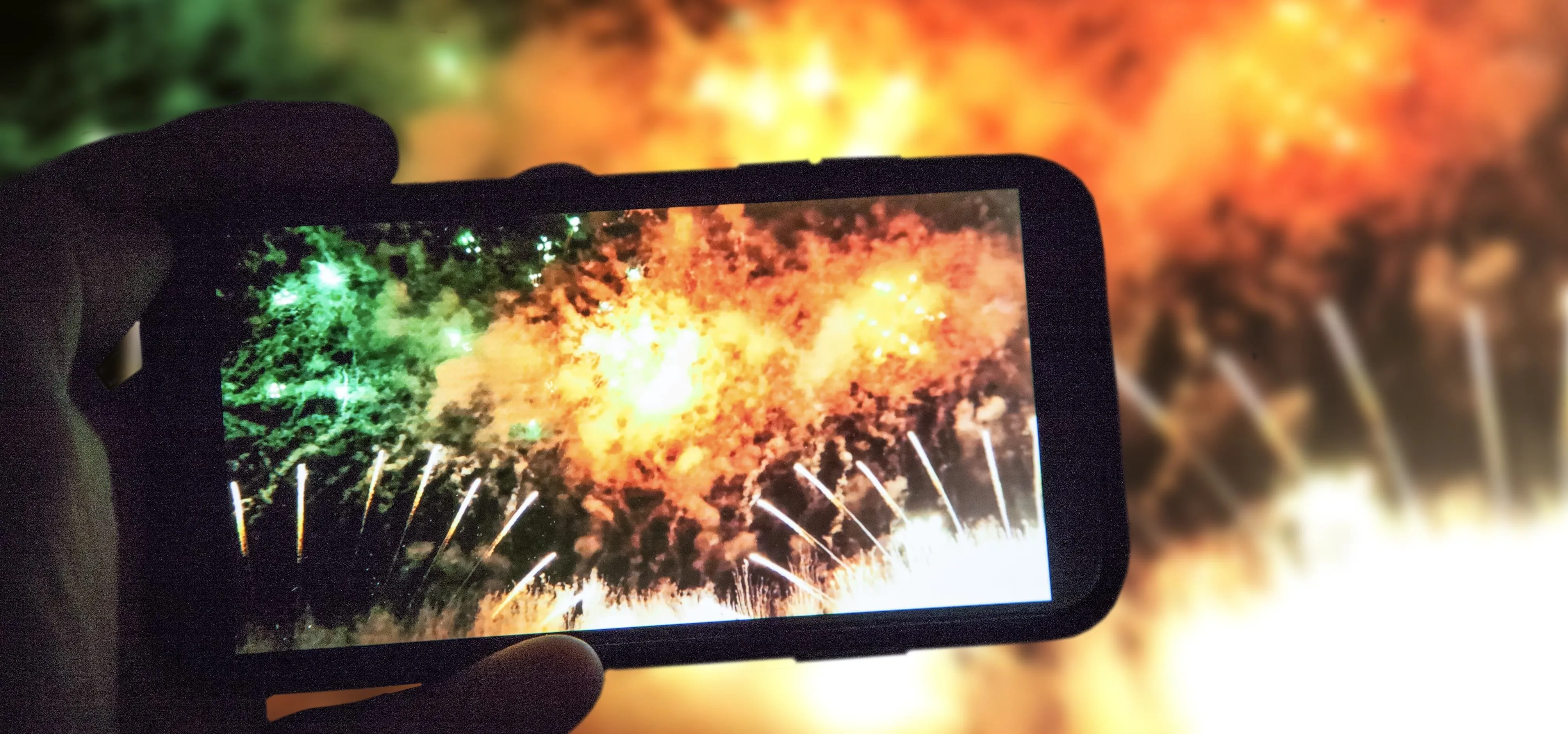 Person capturing a fireworks display on a smartphone.