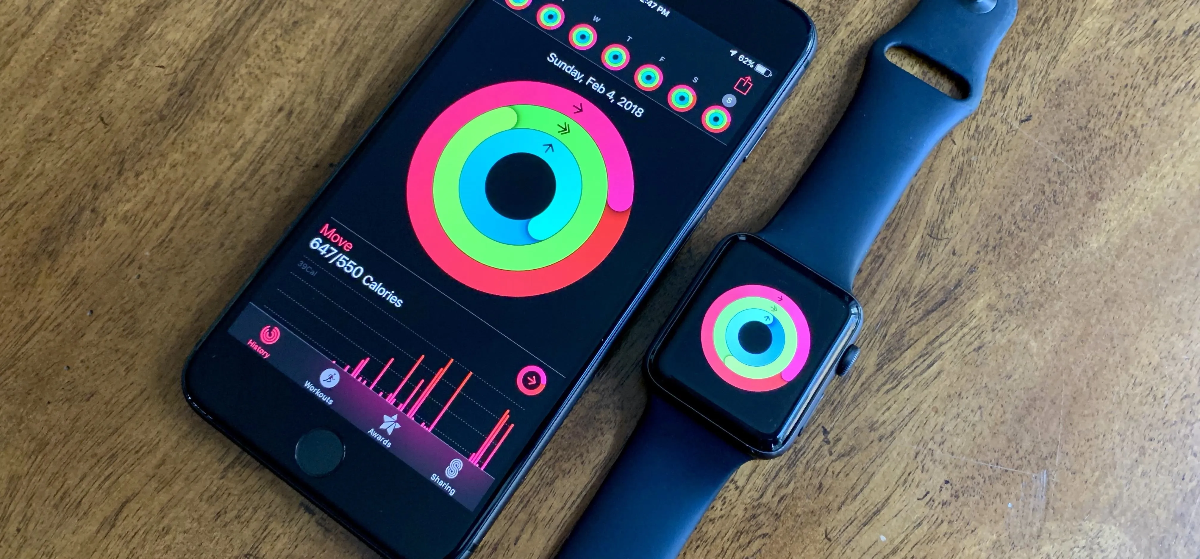 Smartphone and smartwatch displaying fitness tracking metrics on a wooden surface.