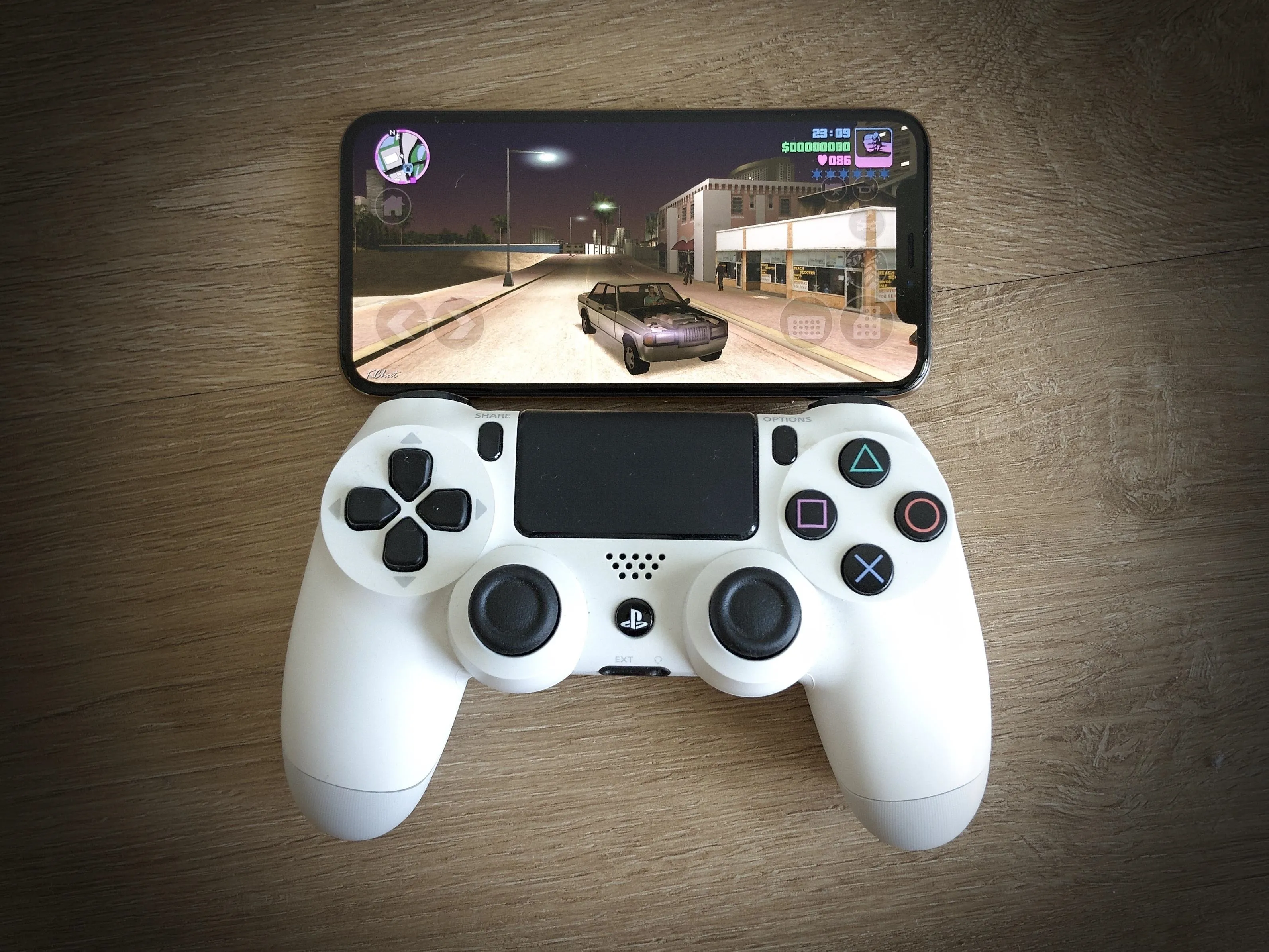 Gaming console controller with a mobile screen displaying a racing game.