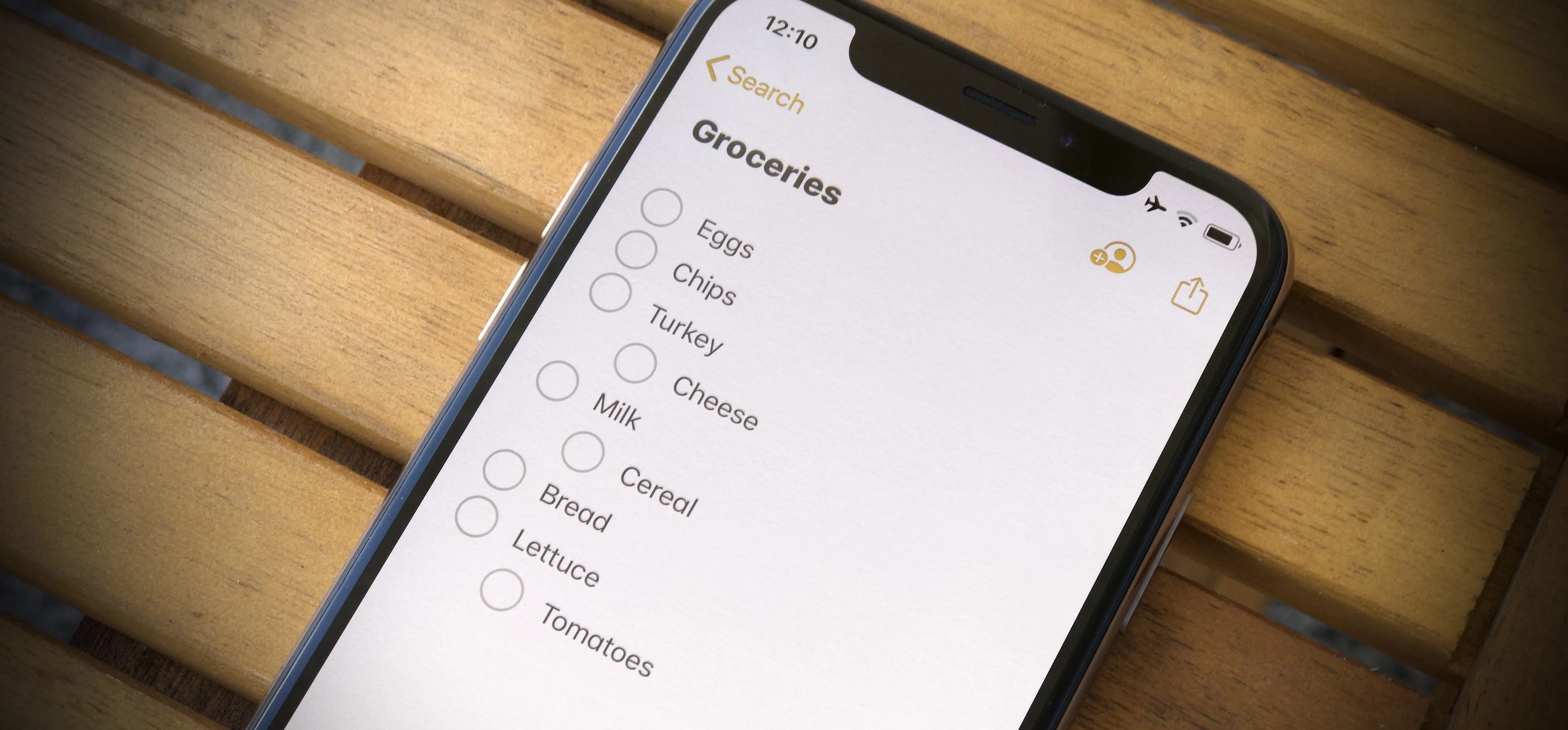 Grocery list on a smartphone screen placed on a wooden surface.